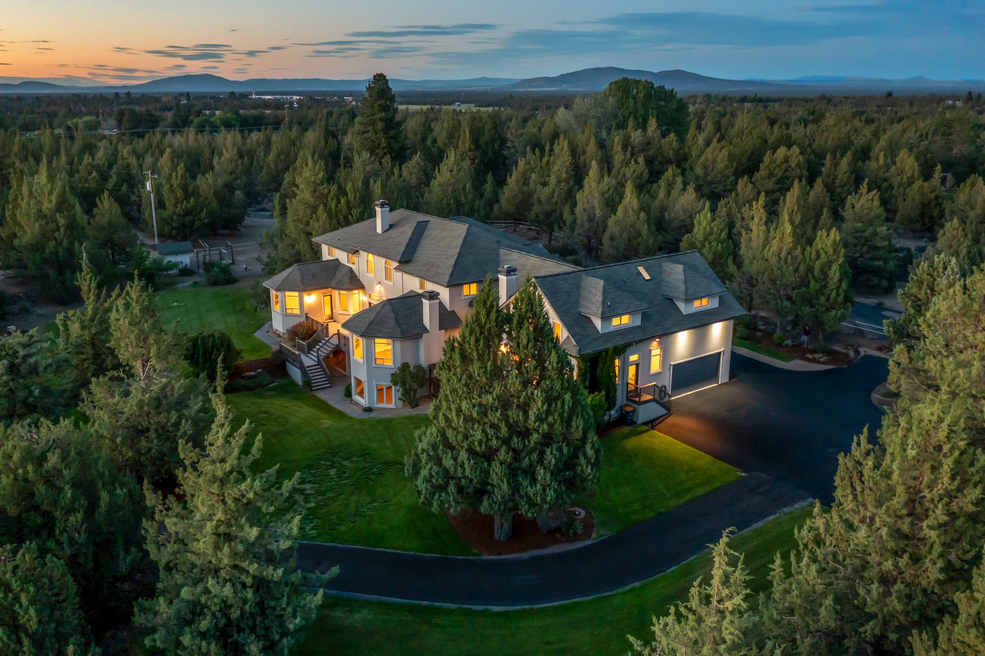 Aerial view of the home and grounds surrounded by pines at dusk
