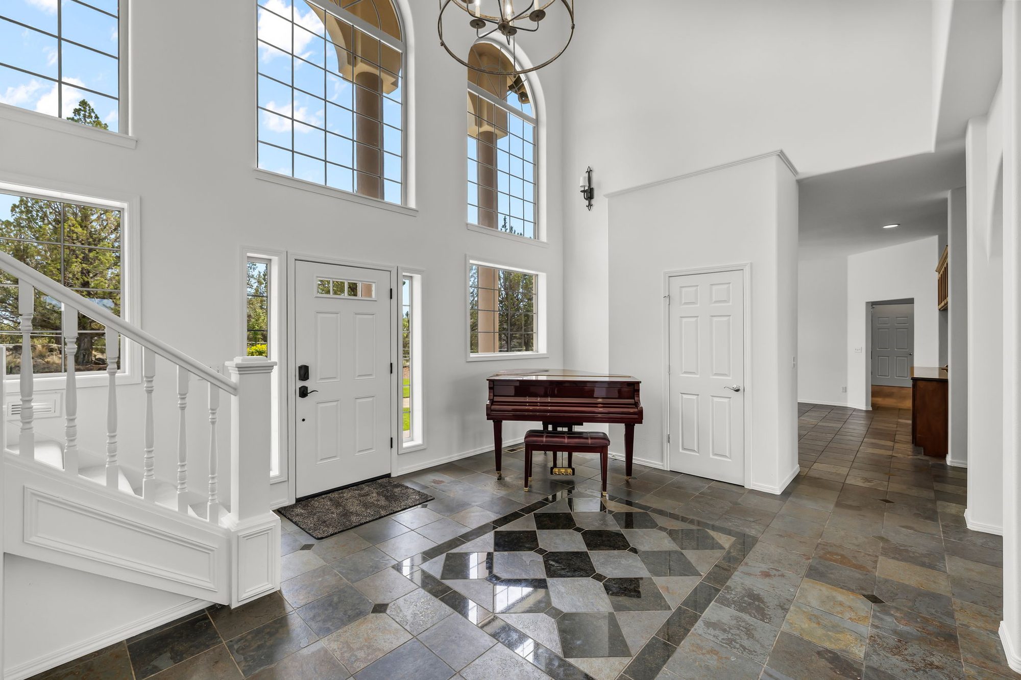 Two-story entry with arched windows and a baby grand piano