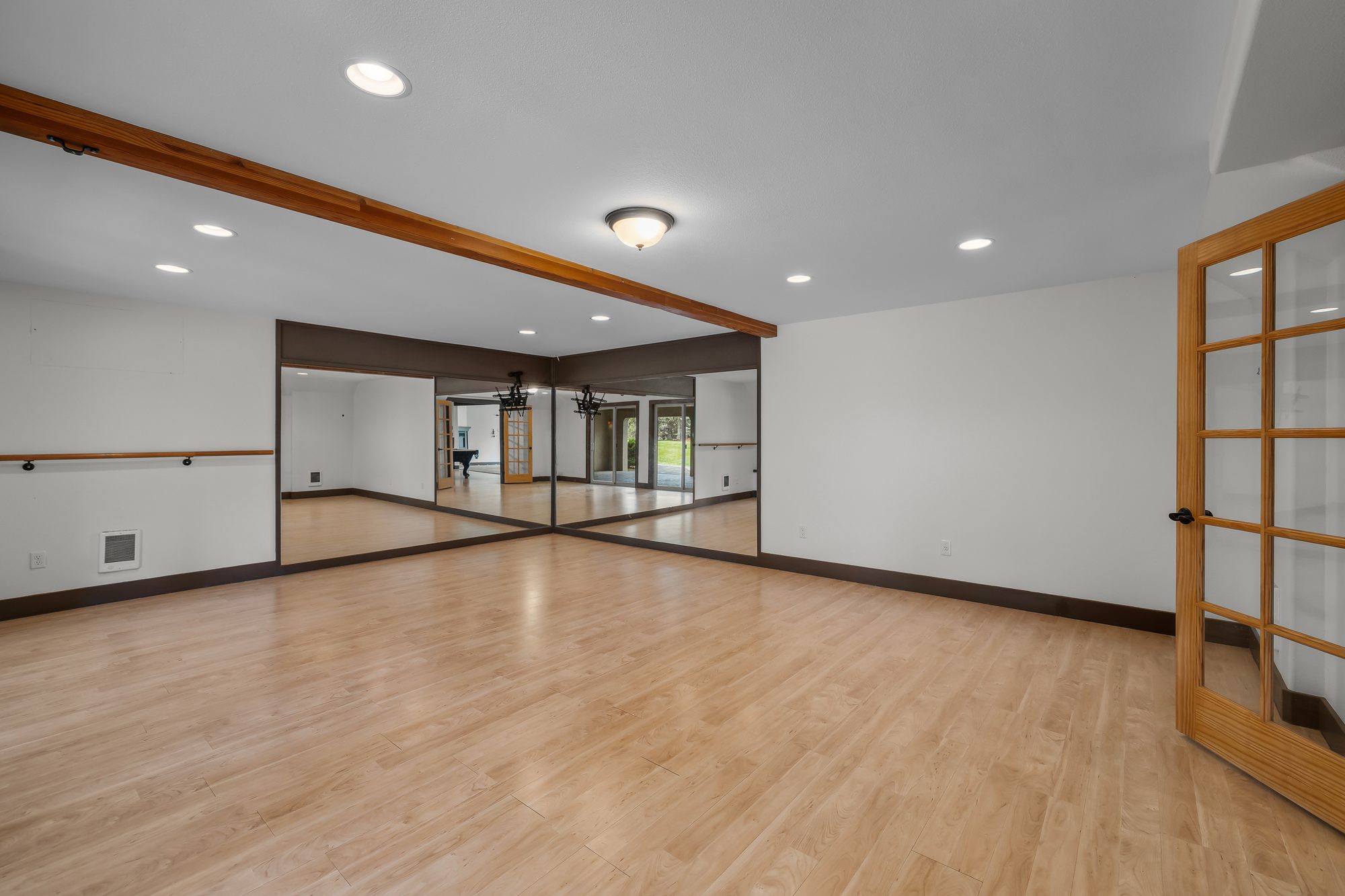 Open flex studio with mirrored wall, ballet barre, and French doors