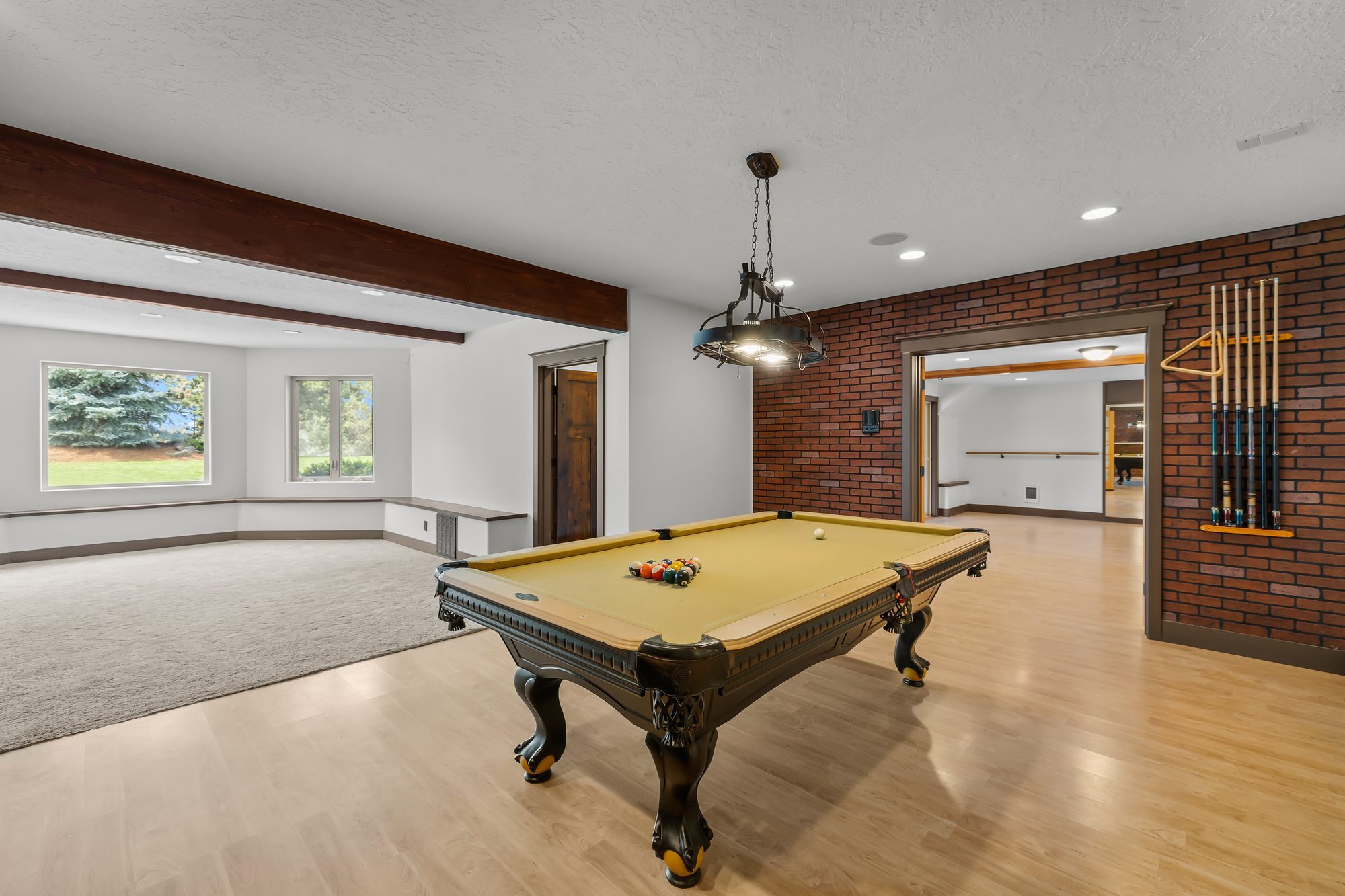 Game room with pool table, exposed brick accent wall, and cue rack