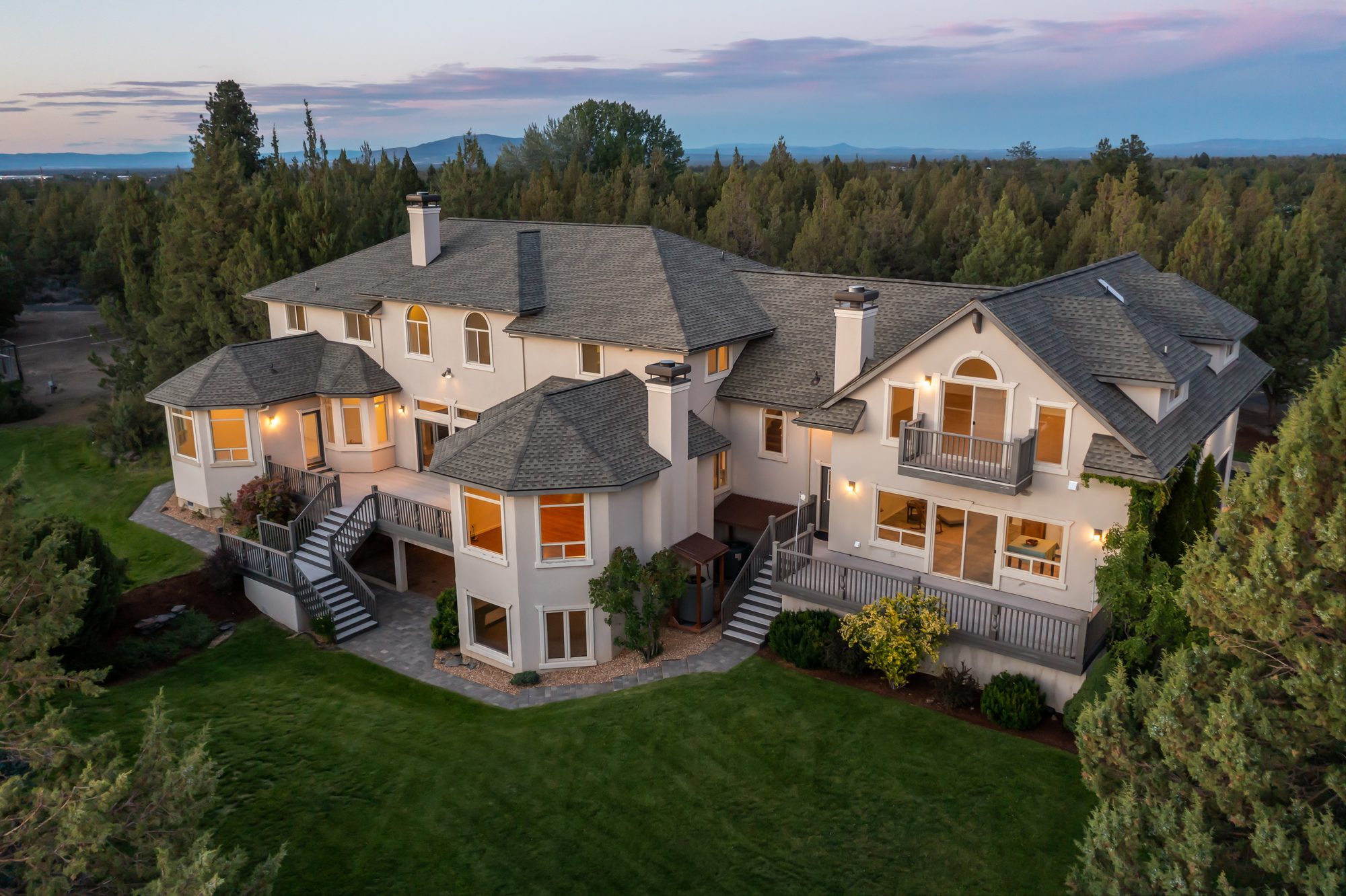 Aerial twilight view of the home, grounds, and distant mountains