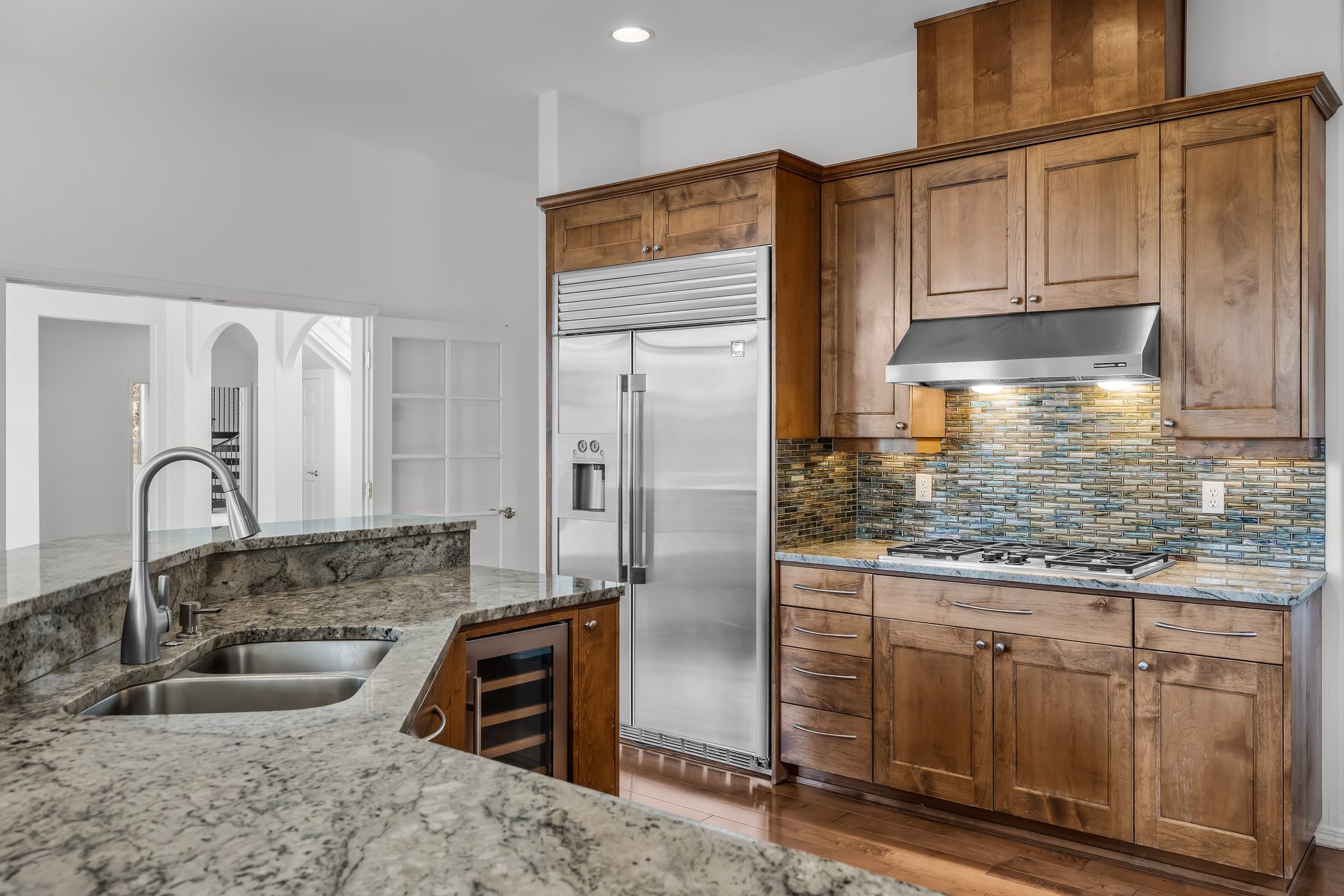 Kitchen with built-in stainless appliances and tile backsplash