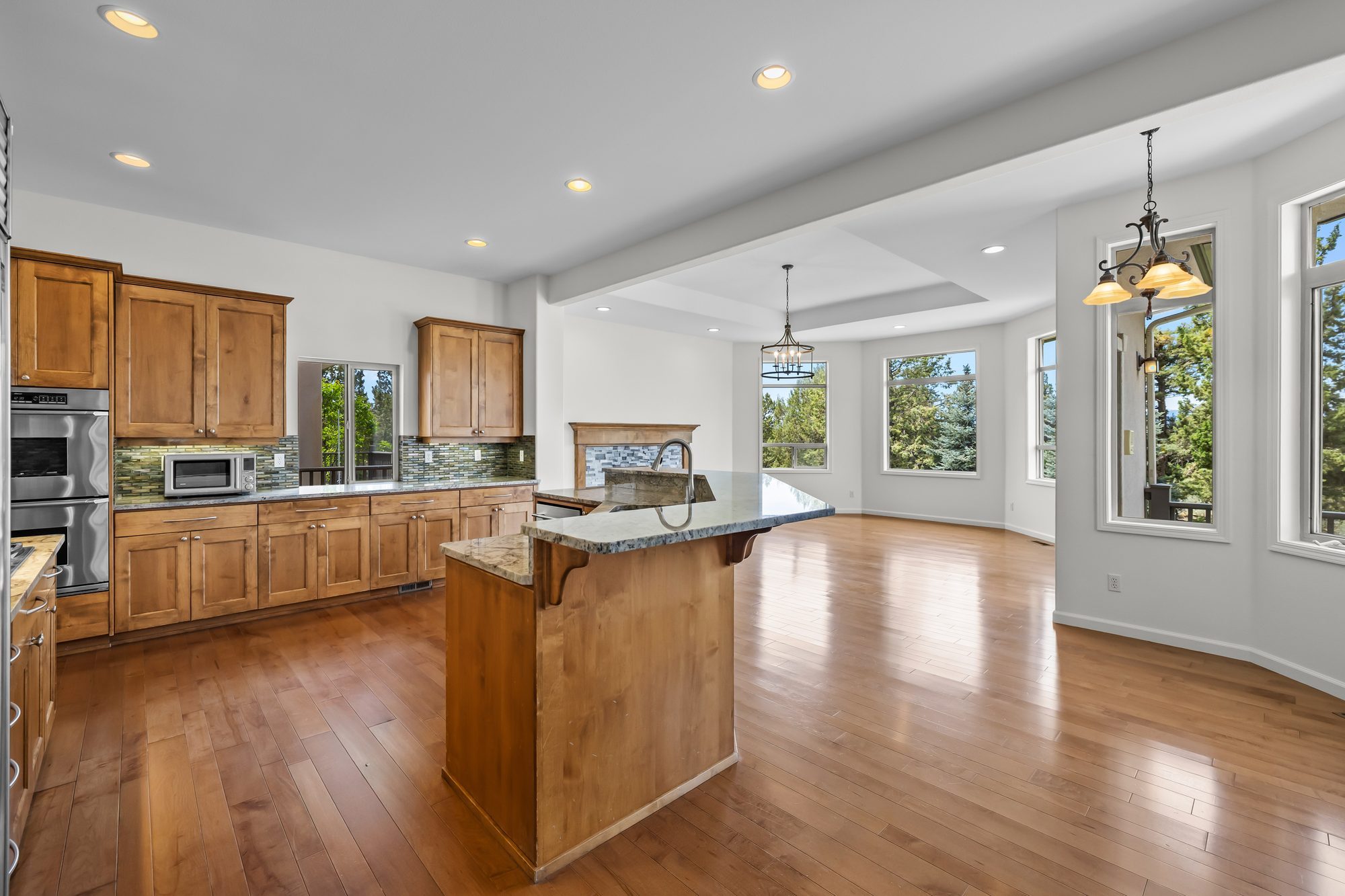 Kitchen island opening onto a breakfast nook with wraparound windows