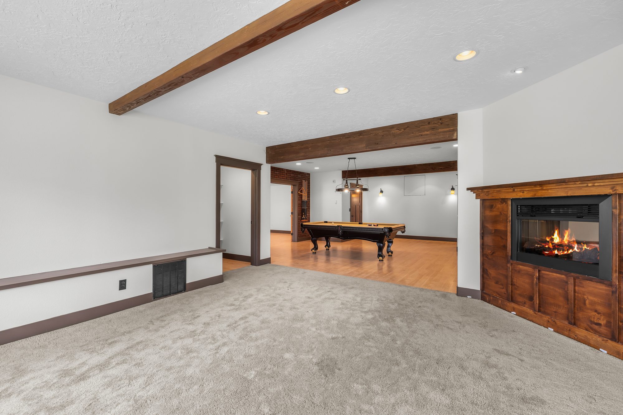 Lower-level media room with built-in fireplace, opening onto the game room