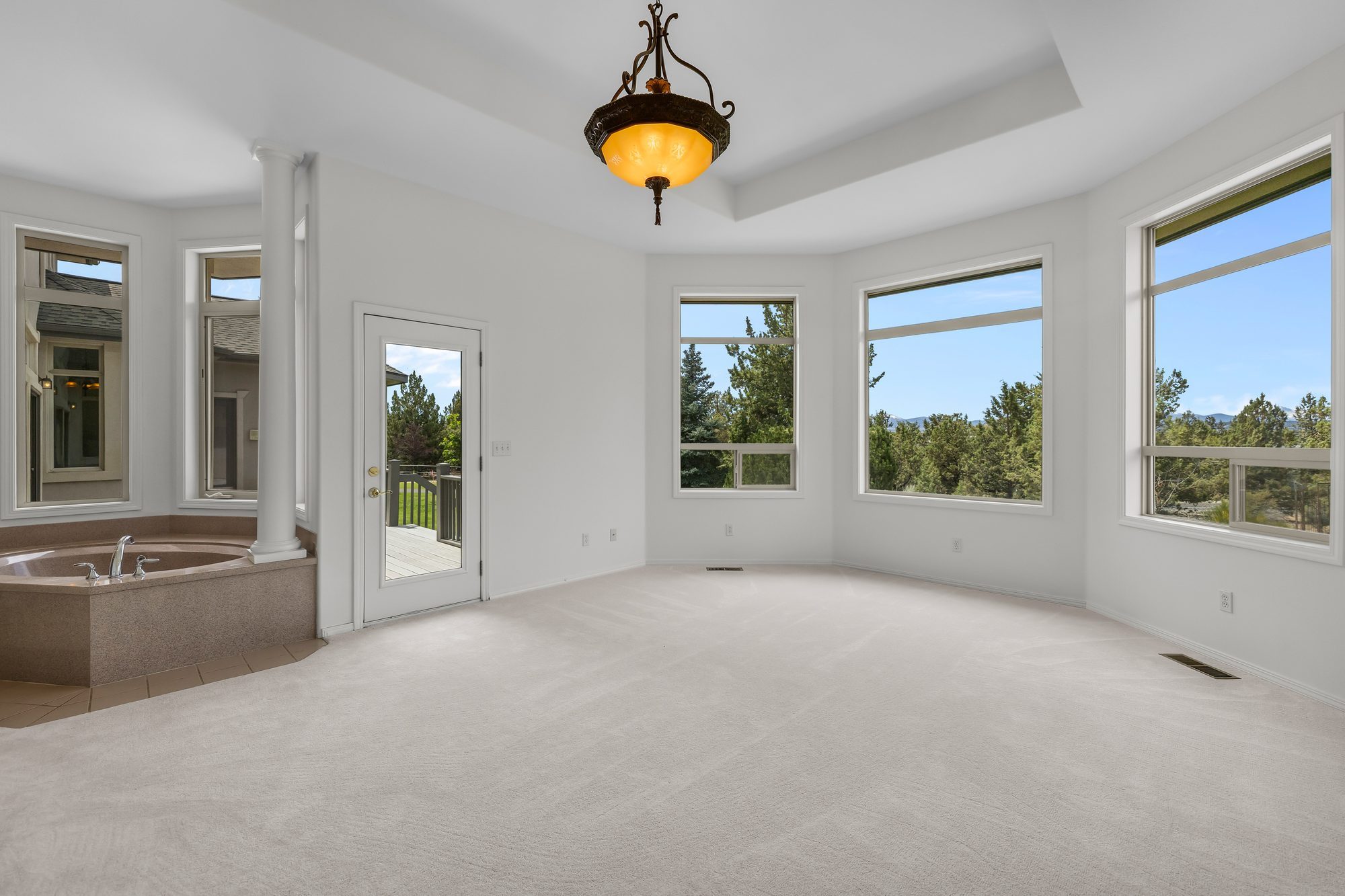 Primary suite with soaking tub, tray ceiling, and deck access